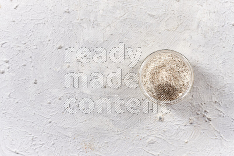 A glass jar full of onion powder on white background