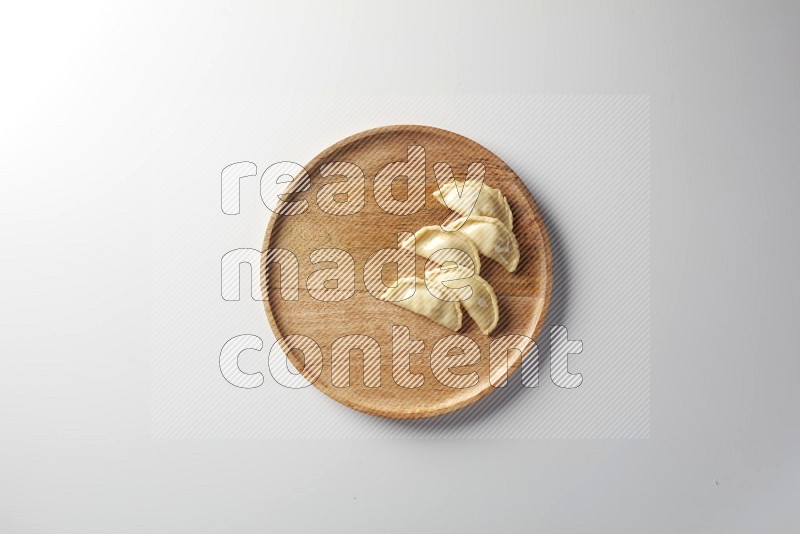 Five Sambosas on a wooden round plate on a white background