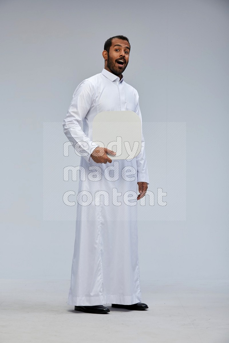 Saudi man wearing Thob standing holding social media sign on Gray background