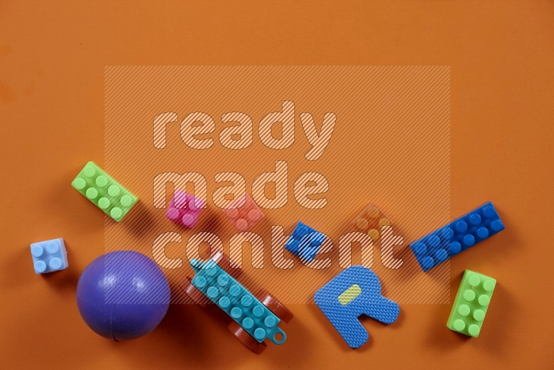 Plastic building blocks with balls on orange background in top view (kids toys)