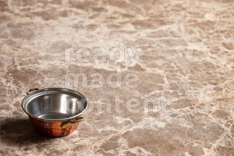 A small copper pot on beige marble background