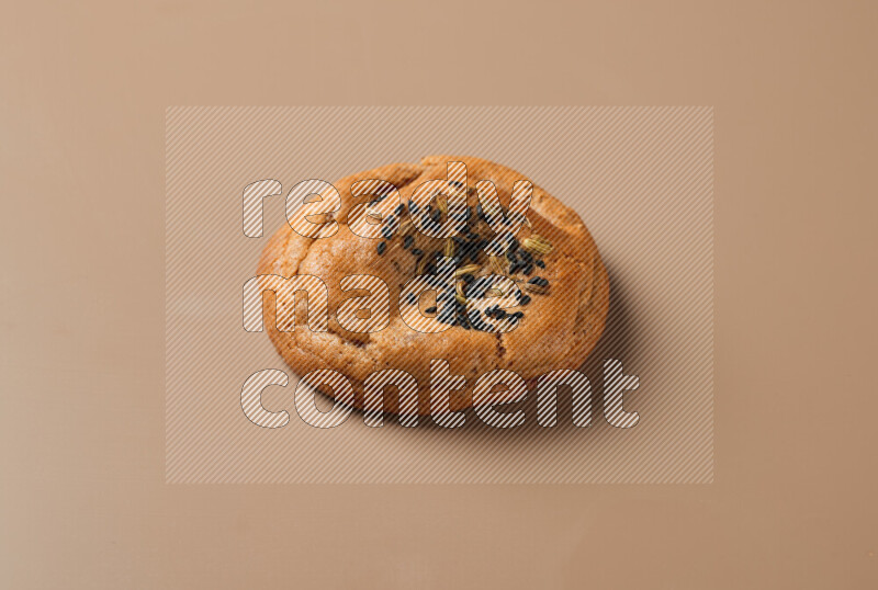 a whole Hasawi cookie with grains on a brown background