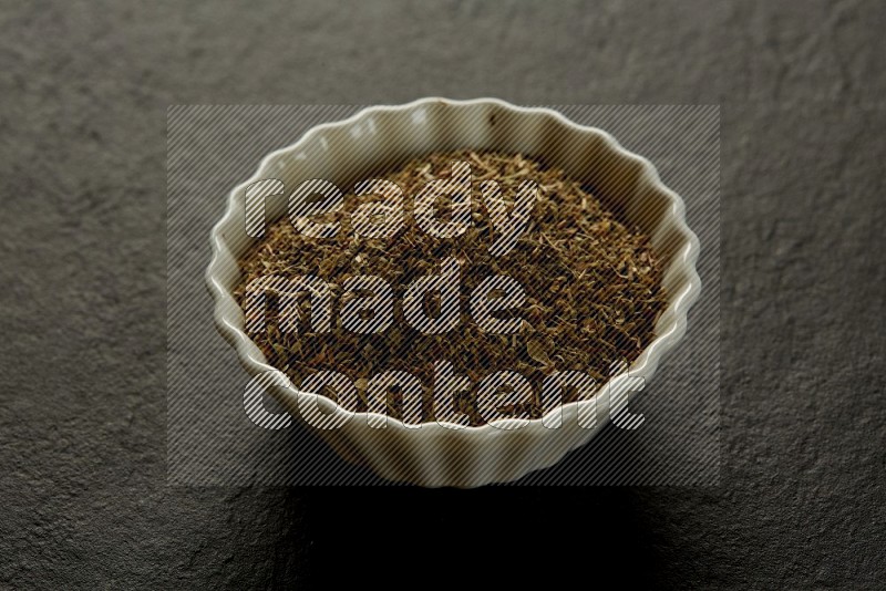 white ceramic round sauce bowl filled with herbs on grey textured countertop