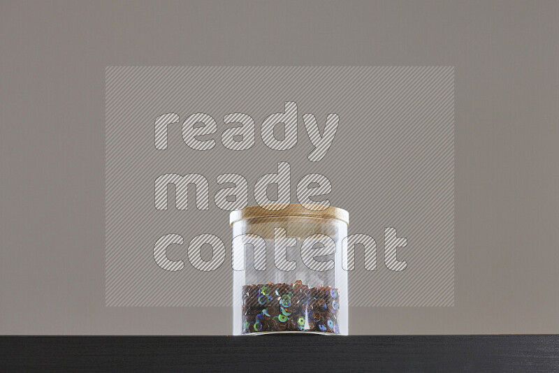 Sequins in a glass jar on black background