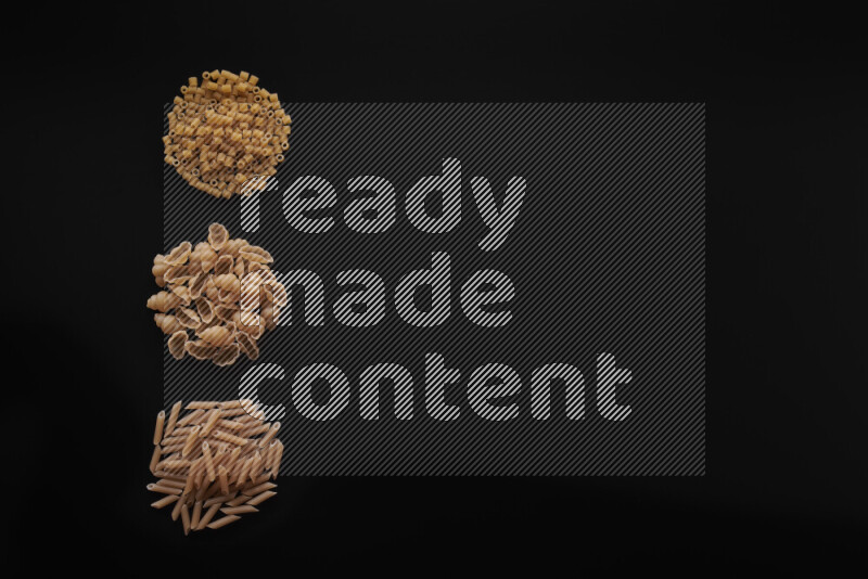 Different pasta types in 3 bunches on black background