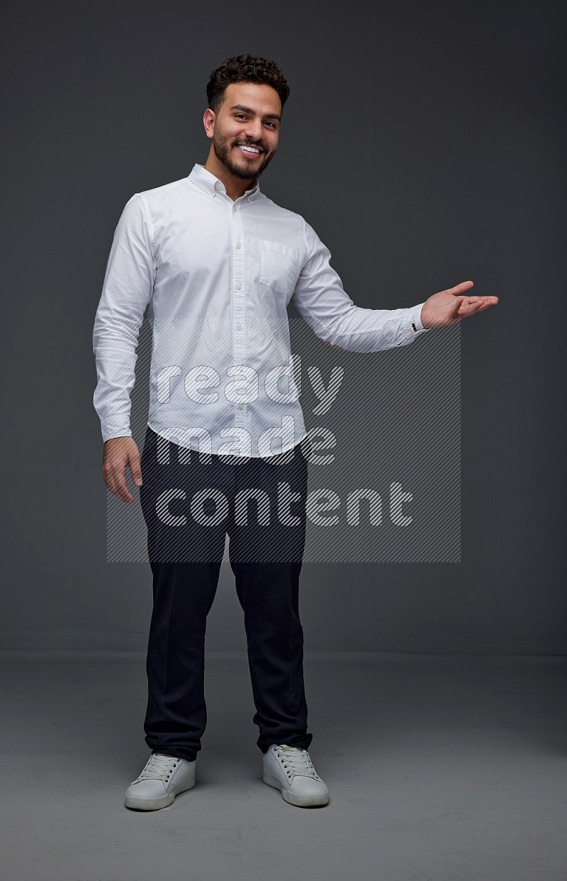 A man wearing smart casual standing and making multi hand gestures eye level on a gray background