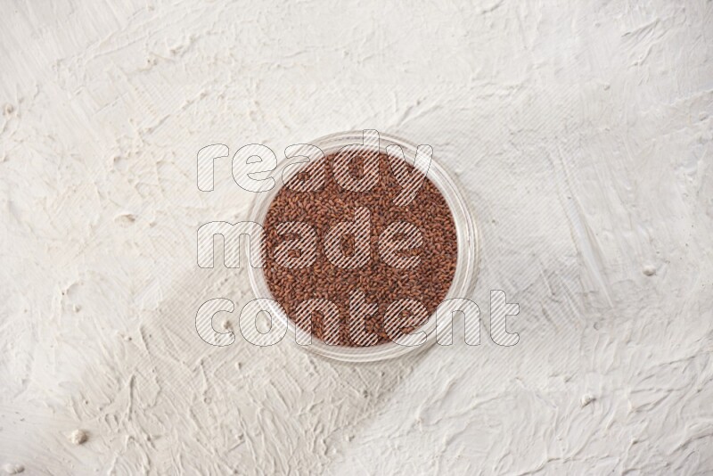 A glass jar full of garden cress seeds on a textured white flooring