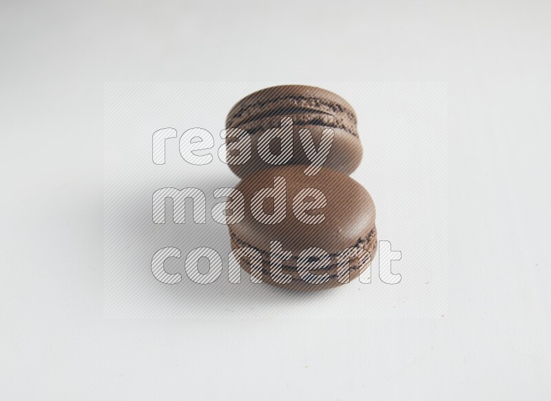 45º Shot of two Brown Dark Chocolate macarons on white background
