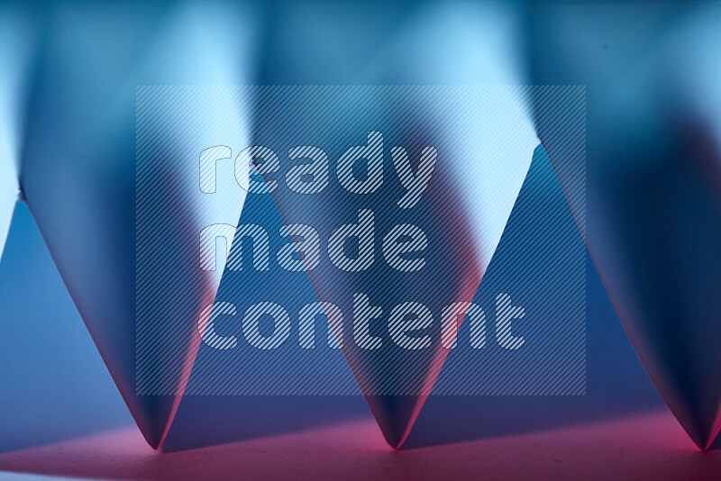 A close-up abstract image showing sharp geometric paper folds in blue and red gradients