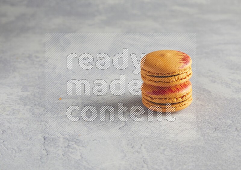 45º Shot of two orange Exotic macarons on white  marble background