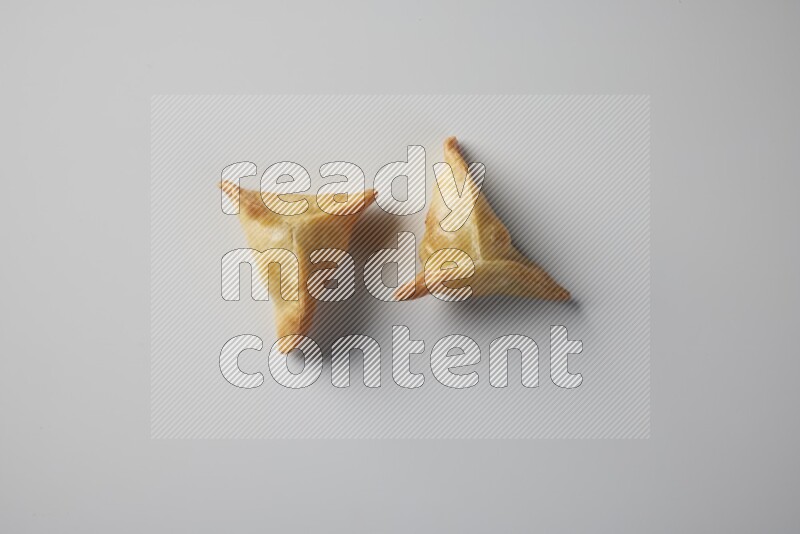 Two fried sambosa from a top angle on a white background