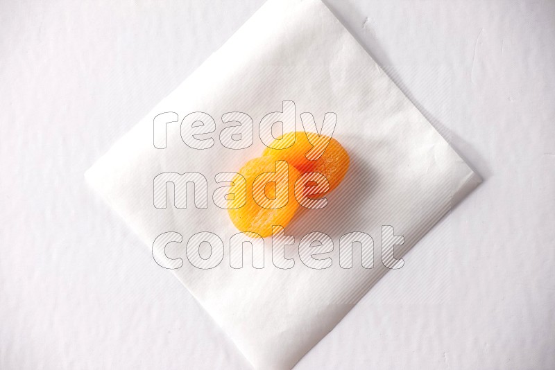 Two dried apricots on a piece of paper on a white background in different angles