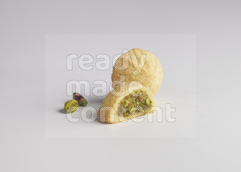 Two Pieces of Maamoul filled with pistachio paste  one of them is cut direct on white background