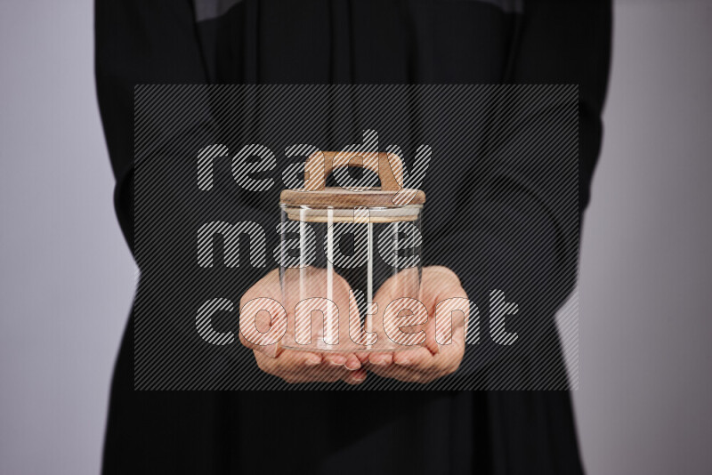 A woman in black abaya holding different glassware in different positions