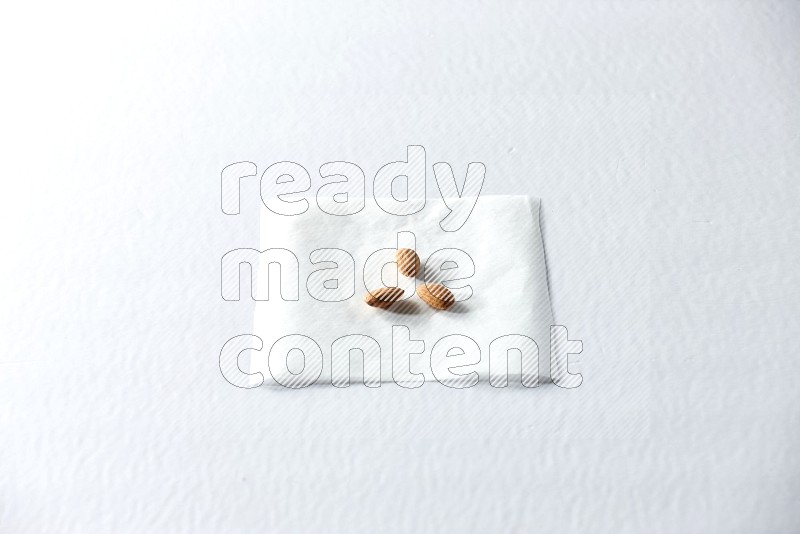 3 peeled almonds on a piece of paper on a white background in different angles