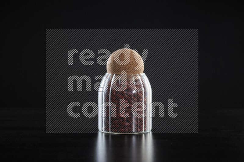 Red kidney beans in a glass jar on black background