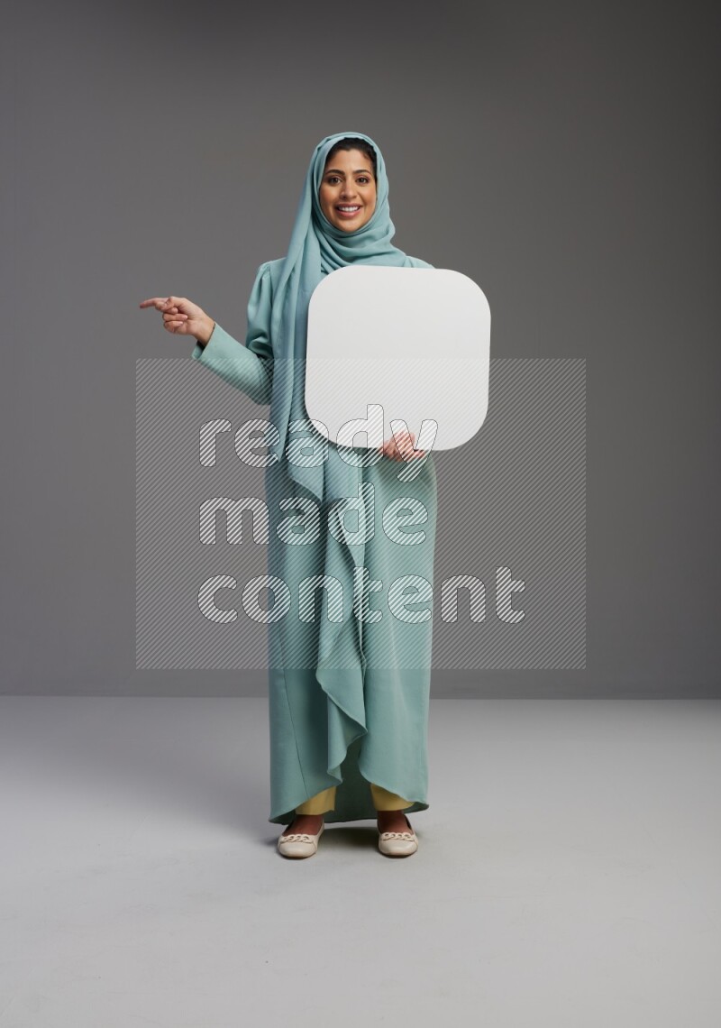 Saudi Woman wearing Abaya standing holding social media sign on Gray background