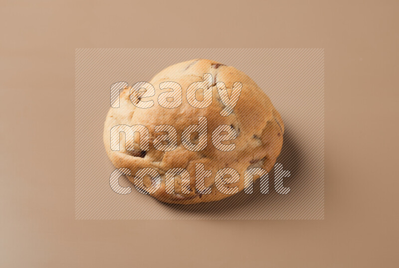 a whole chocolate chip cookie on a brown background