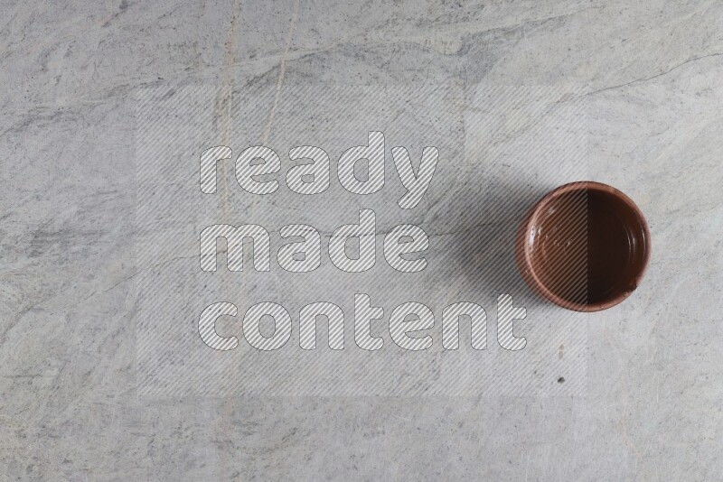 A brown pottery bowl on grey marble background