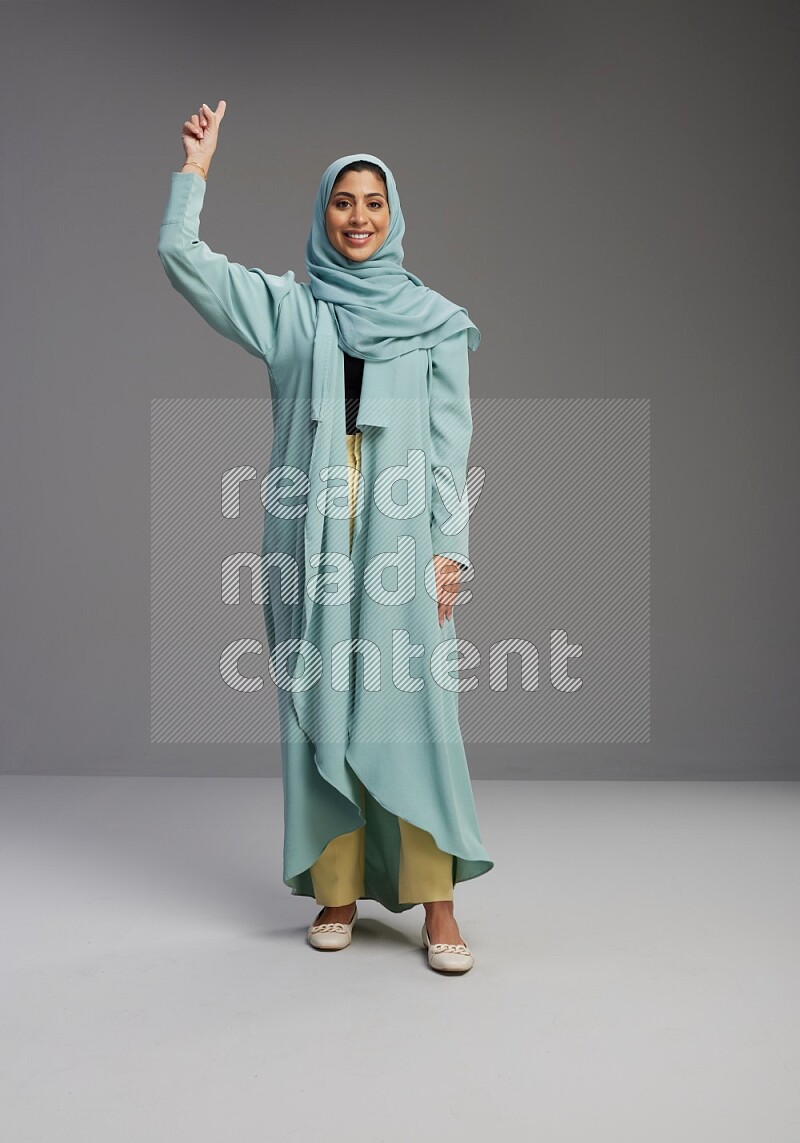 Saudi Woman wearing Abaya standing interacting with the camera on Gray background