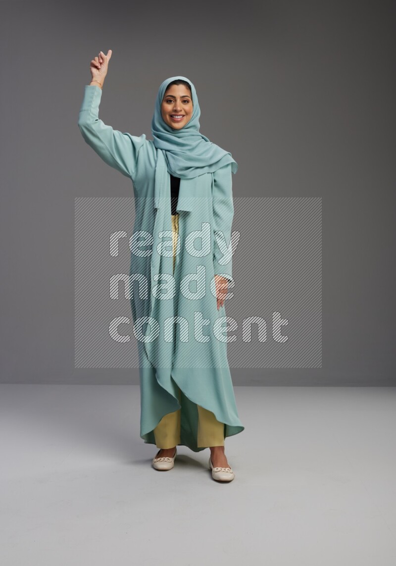 Saudi Woman wearing Abaya standing interacting with the camera on Gray background