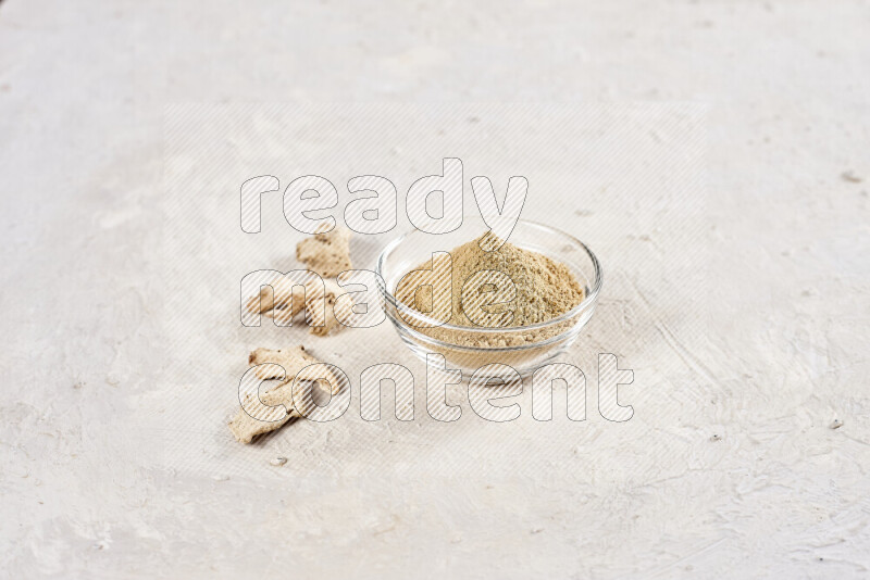 A glass bowl full of ground ginger powder on white background