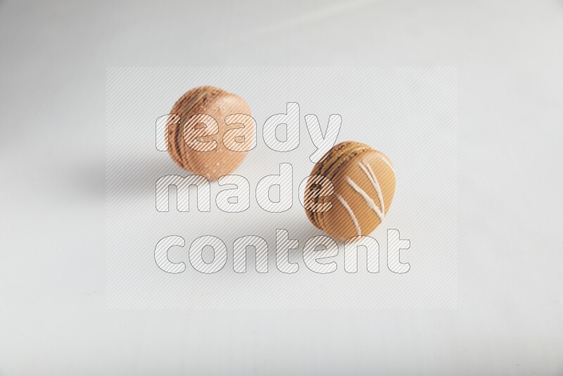 45º Shot of of two assorted Brown Irish Cream, and Brown Hazelnuts macarons on white background