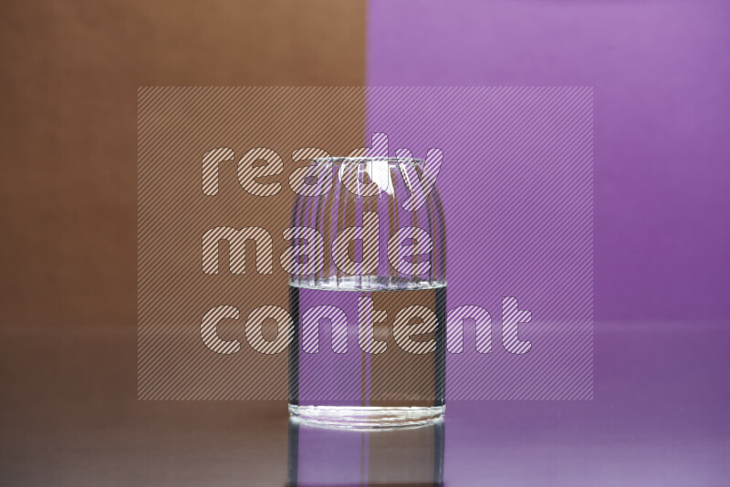 تظهر الصورة أواني زجاجية ممتلئة بالماء موضوعة على خلفية من اللونين البني والأرجواني