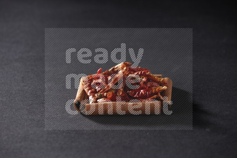 A single square of cinnamon sticks full of chilis on black flooring