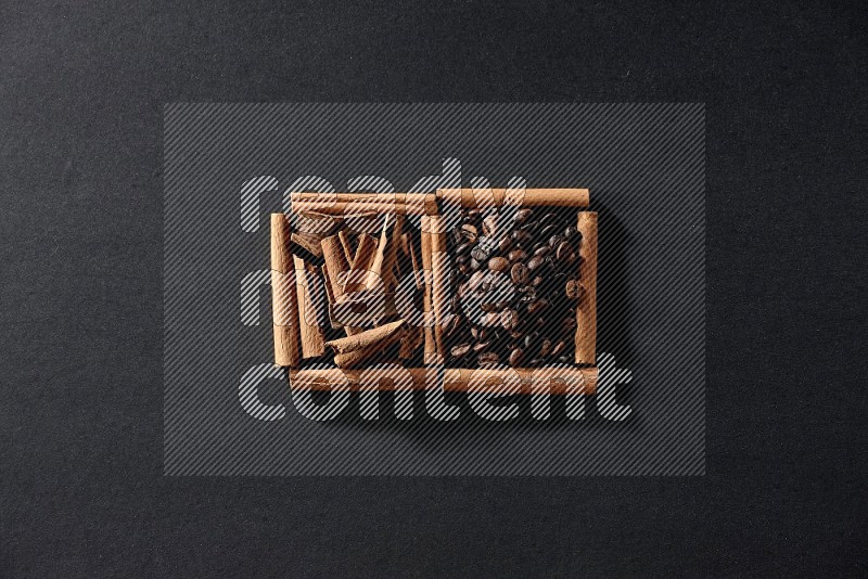 مربعان من أعواد القرفة ممتلئان بحبوب القهوة وقطع من القرفة علي خلفية سوداء