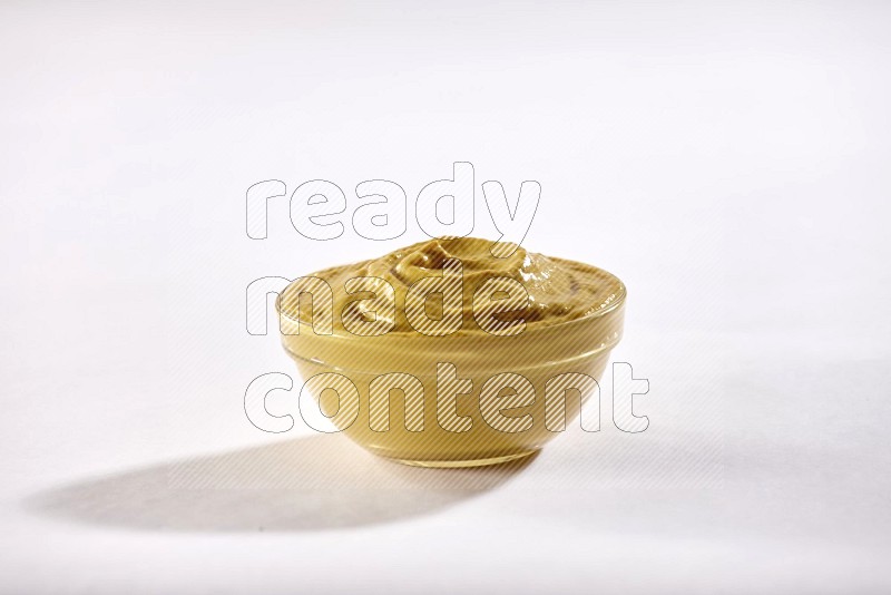A glass bowl full of mustard paste on a white flooring in different angles