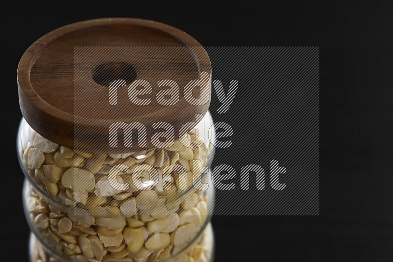 Crushed beans in a glass jar on black background