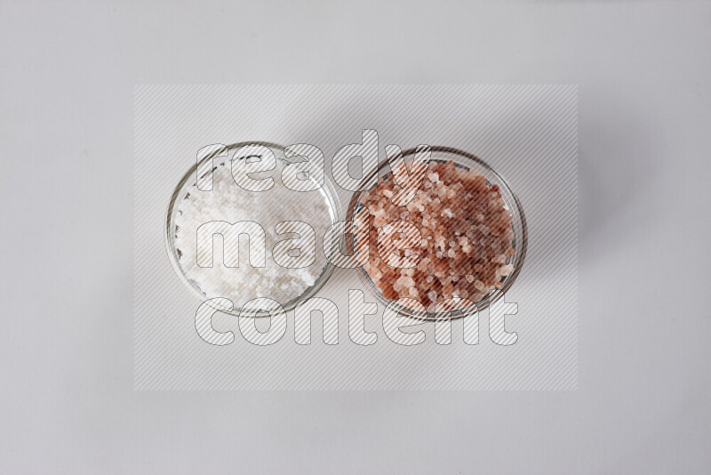 4 glass bowls filled with table salt, coarse sea salt, fine himalayan salt and coarse himalayan salt on white background