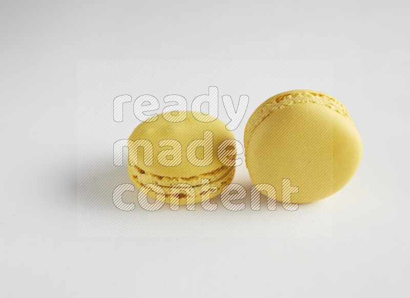 45º Shot of two Yellow Lemon macarons on white background