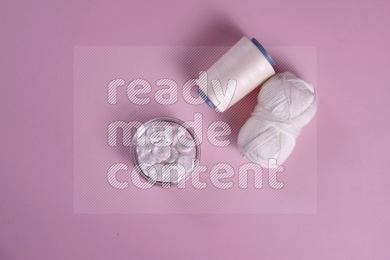 White sewing supplies on pink background