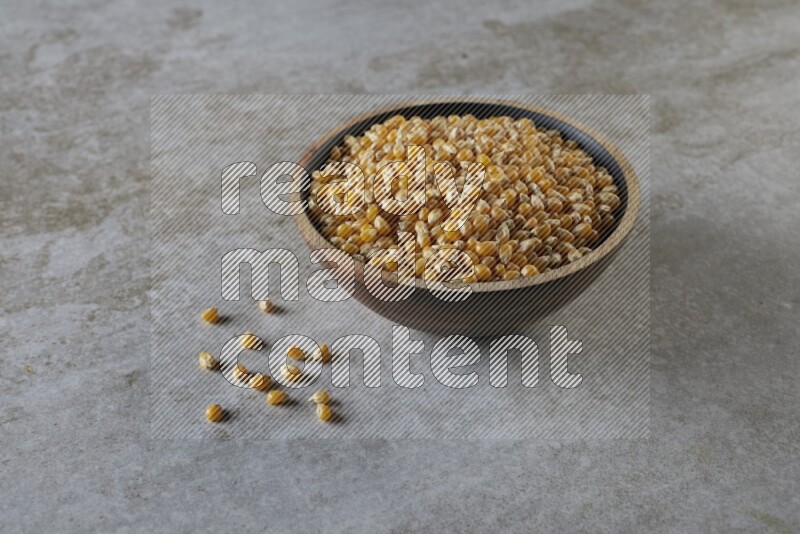 corn kernel in a wooden bowl on a grey textured countertop
