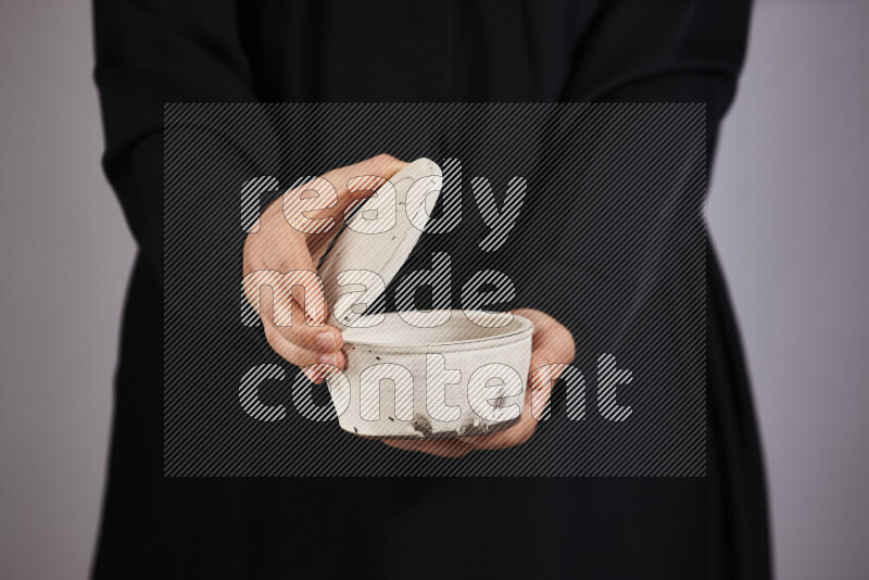 A woman in black abaya holding different pottery essentials in different positions