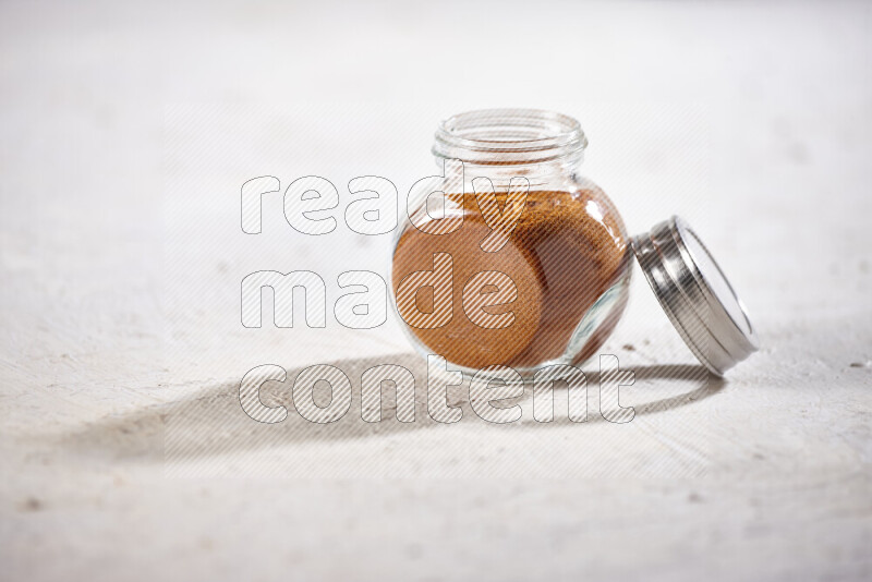 A glass jar full of ground paprika powder on white background