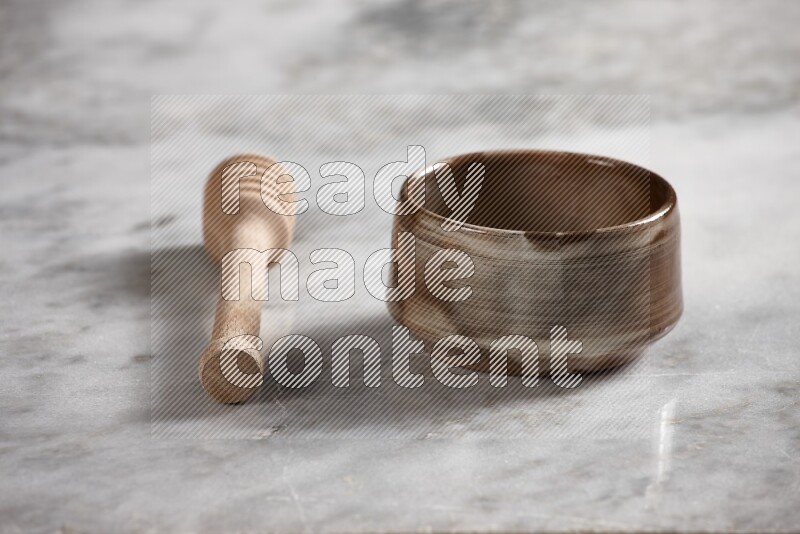 وعاء فخاري متعدد الألوان مع ملعقة عسل خشبية بجانبه على خلفية رخام رمادي