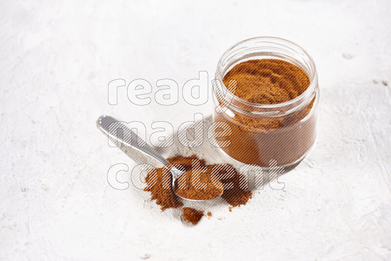 A glass jar full of ground paprika powder on white background