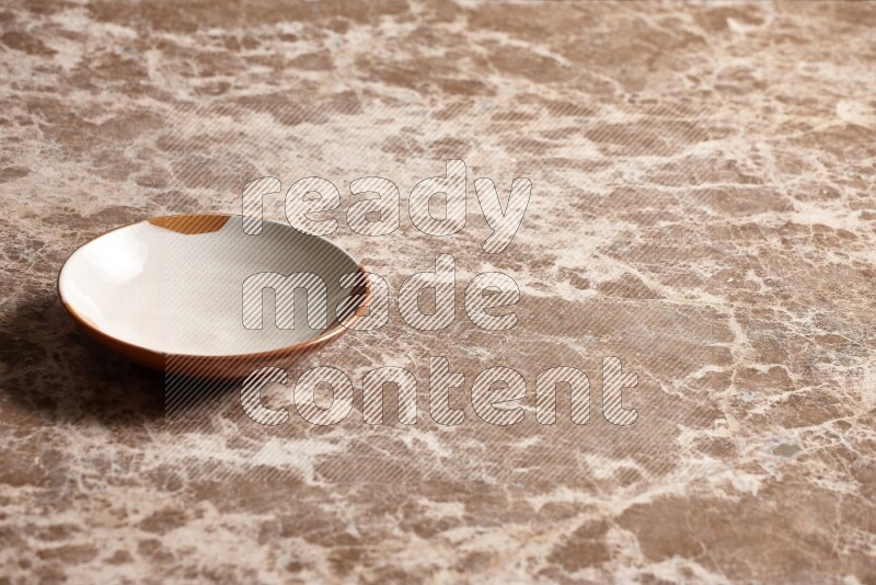 A multicolored pottery plate on beige marble background