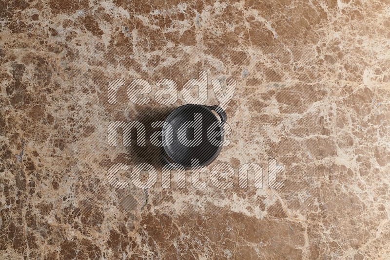 Top View Shot Of A Black Pottery Bowl On beige Marble Flooring