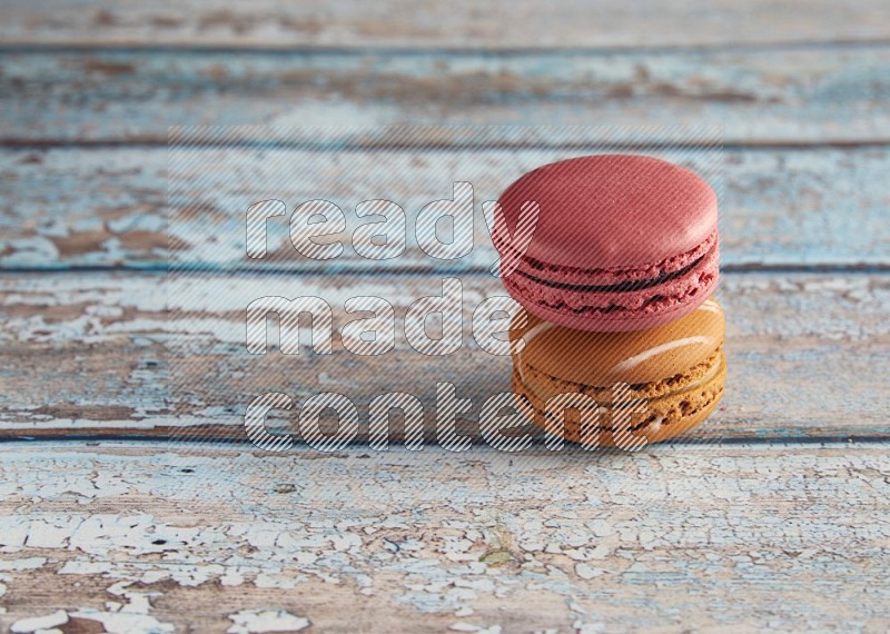 45º Shot of of two assorted Brown Irish Cream, and Pink Raspberry macarons on light blue background