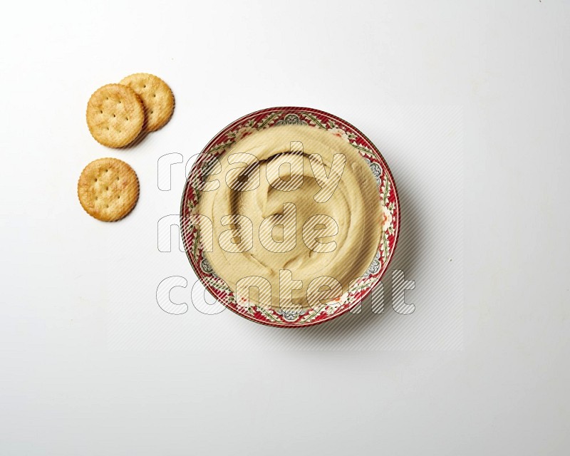 Plain Hummus in a red plate with patterns on a white background