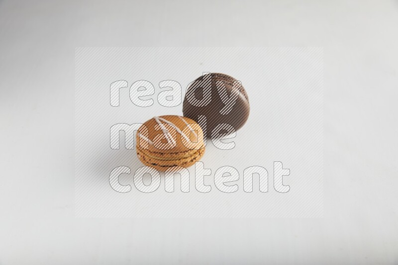 45º Shot of of two assorted Brown Irish Cream, and Brown Dark Chocolate macarons on white background