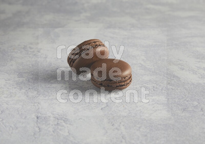 45º Shot of two Brown Dark Chocolate macarons  on white  marble background