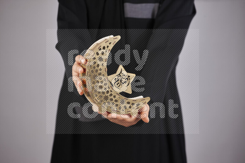 A woman in black abaya holding different ramadan lanterns in different positions