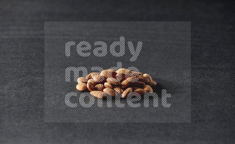 A bunch of peeled almonds on a black background in different angles