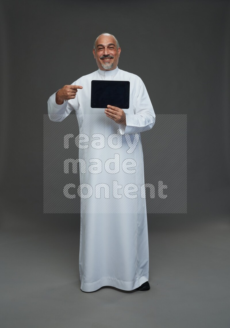 Saudi man without shomag Standing working on tablet on gray background
