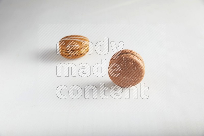 45º Shot of of two assorted Brown Irish Cream, and Brown Hazelnuts macarons on white background